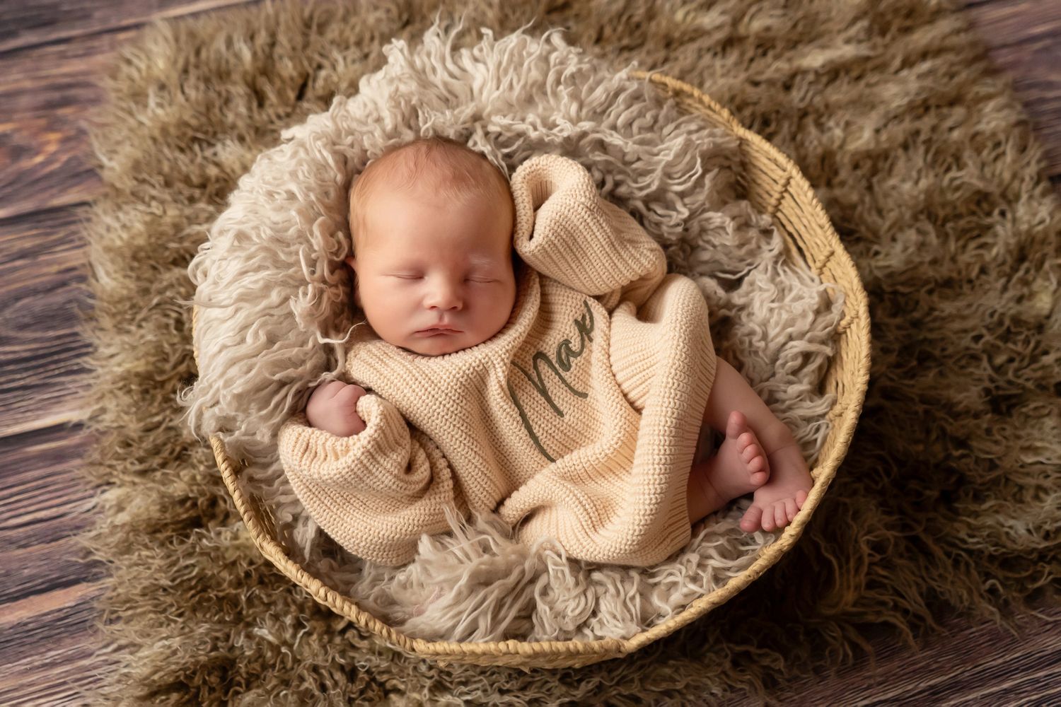 Newborn baby peacefully sleeping in a cozy basket with soft blankets.