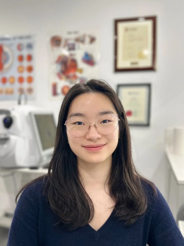 Young woman with glasses smiling indoors.