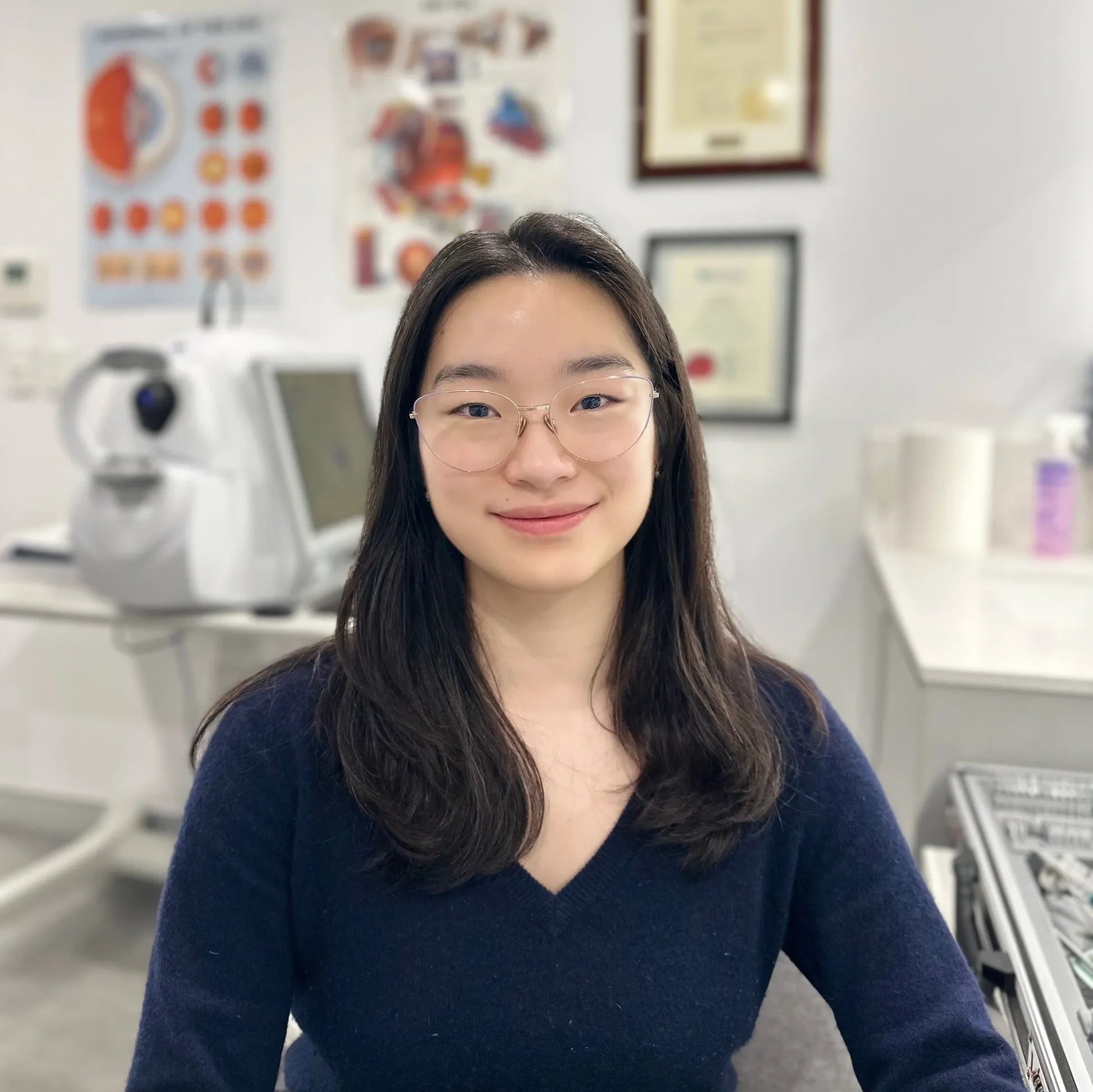 Smiling woman with glasses in a medical setting.