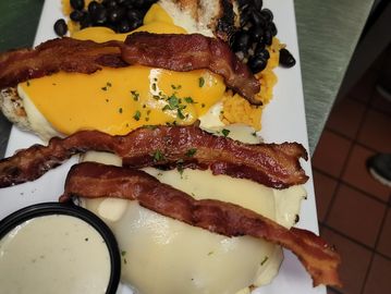 Plate of eggs with melted cheese, bacon, and black beans.