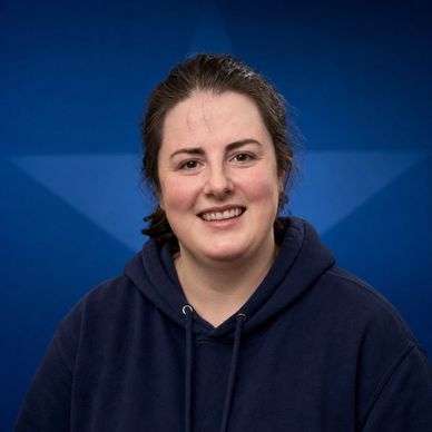 Smiling woman in a navy hoodie.