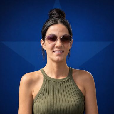 Woman in sunglasses and green tank top in front of a blue star background.