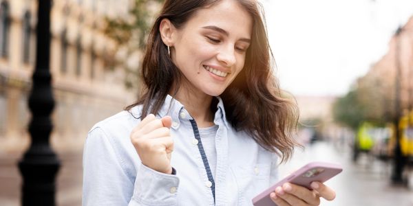 mujer feliz mirando su teléfono móvil en señal de aprobación