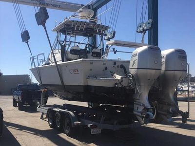 Twin BF250 Honda outboards coming in for service.  Boston Whaler is being hoisted onto boat trailer.