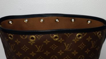 Close-up of a Louis Vuitton bag top with eyelet details and monogram pattern.