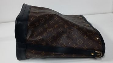 A Louis Vuitton patterned brown leather bag lying on its side.