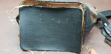 Bottom view of a worn Louis Vuitton bag on a workbench with tools.