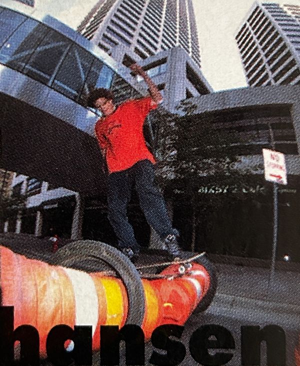Skateboarder performing a trick on a traffic cone in an urban setting.