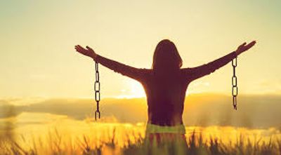 Person breaking free from chains at sunrise.