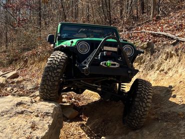 Green Jeep flexing with suspension travel