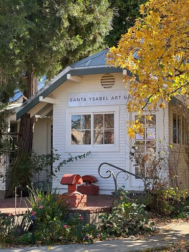 Charming white building of Santa Ysabel Art Gallery surrounded by autumn foliage.