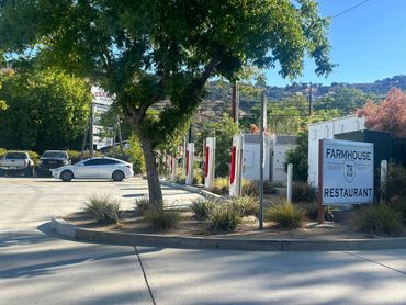 Tesla cars charging at Farmhouse 78 restaurant in a sunny outdoor setting.