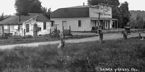 Old black and white photo of Santa Ysabel, California, with rustic buildings and a dirt road.