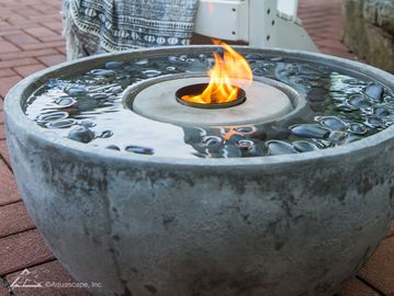 fire and water fountain lit with water on surface in backyard