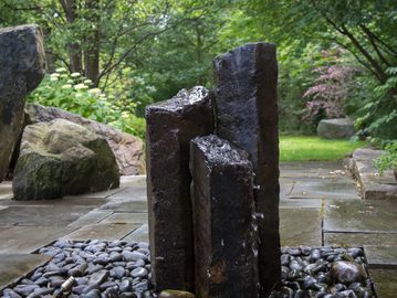 faux basalt columns with water running installed in backyard