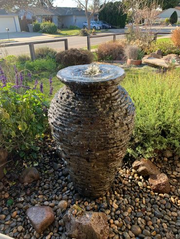 Stacked Slate Urn installed with flowing water and plants in the background