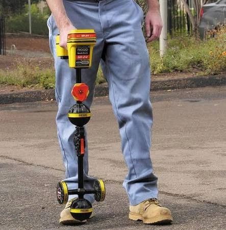 Person holding a Ridgid scanner tool outdoors.