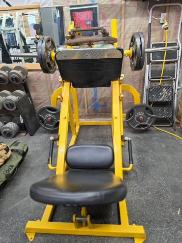 Yellow leg press machine in a gym.