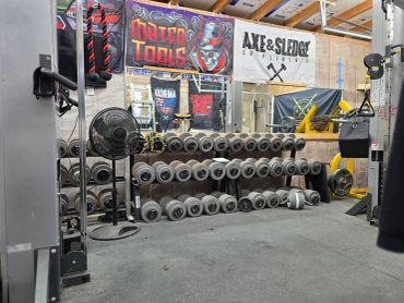 Rows of dumbbells and weightlifting equipment in a gym.