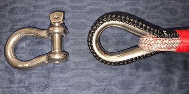 A red rope with a metal loop and a metal shackle on a fabric background.