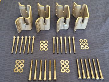 Metal brackets with screws and washers neatly arranged on a surface.