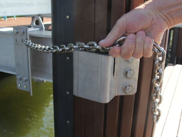 Person holding a metal chain attached to a dock post.