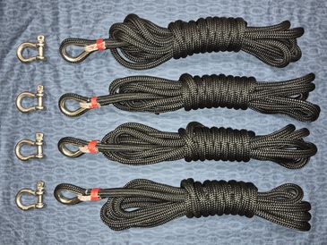 Four coiled black ropes with metal hooks and shackles laid out on a blue surface.