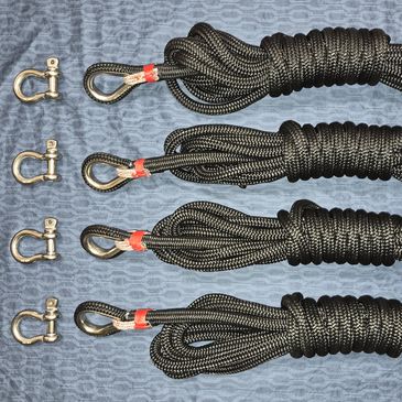 Four black ropes with metal hooks and shackles arranged on a blue surface.