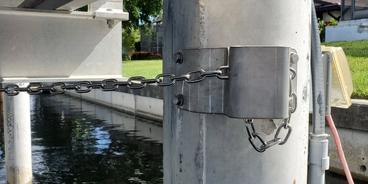 A metal chain secured to a concrete pillar near water.