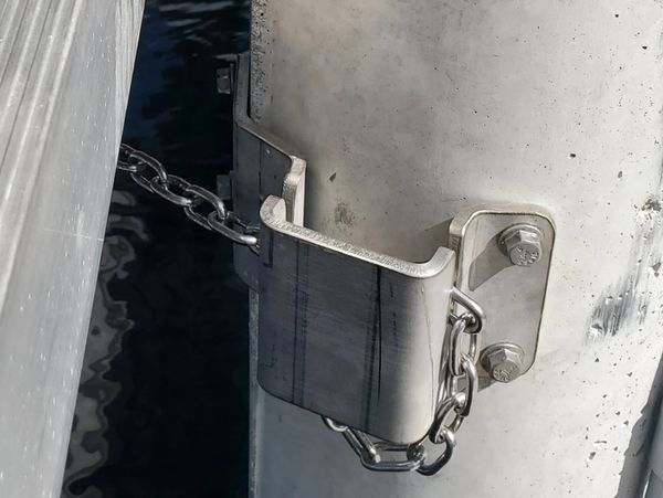 Metal chain securing a dock cleat to a concrete pillar.