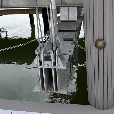 Metal pulley system attached to a dock over water.