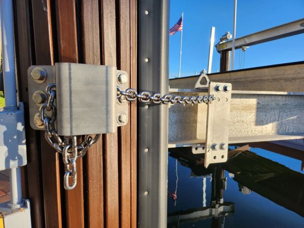 A metal chain secured between two posts with a padlock under a clear sky.