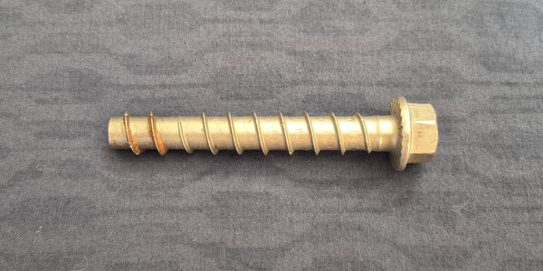 A large hex bolt screw on a dark fabric background.