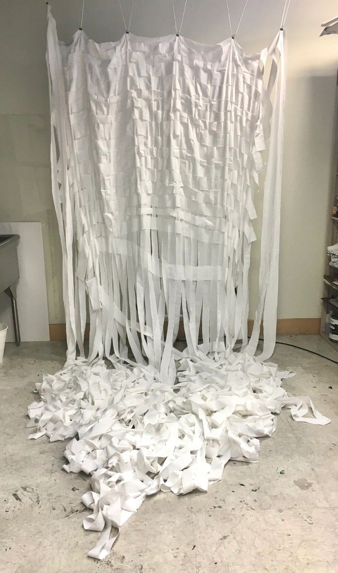 Photograph of a white woven fabric veil hanging from a ceiling in a room