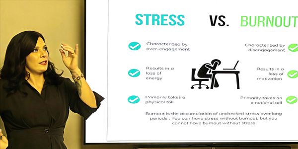 A woman presenting a slide comparing stress and burnout with key differences.