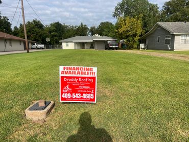 A lawn sign advertising Droddy Roofing with financing available in front of a house.
