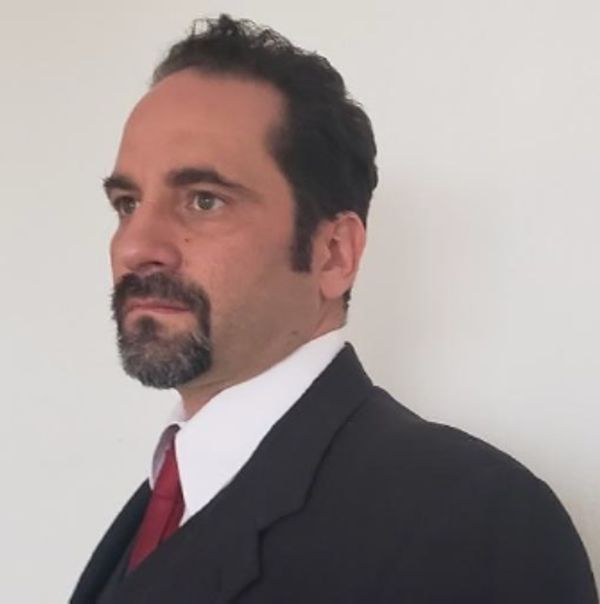 Man in a suit with a red tie looking to the side.