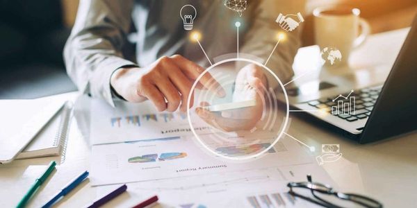 Businessman using smartphone with digital business icons overlaid.
