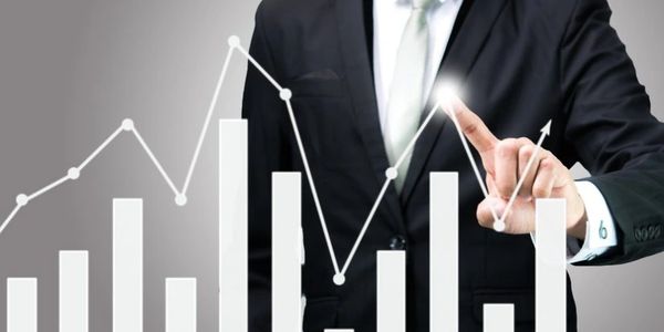Businessman pointing at a rising digital graph showing growth.