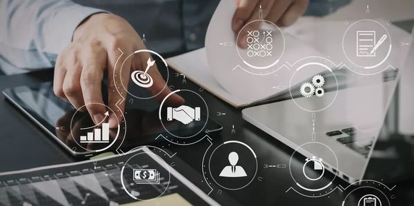 Person working with digital business strategy icons overlaid on a laptop and tablet.