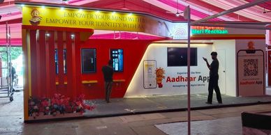 Aadhaar App service kiosk with two people interacting.
