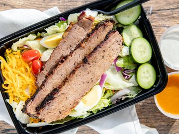 Chef salad topped with brisket, cucumber, egg, tomato and cheese.