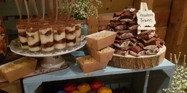 A rustic dessert display with layered parfaits, strawberry brownies, and cupcakes.