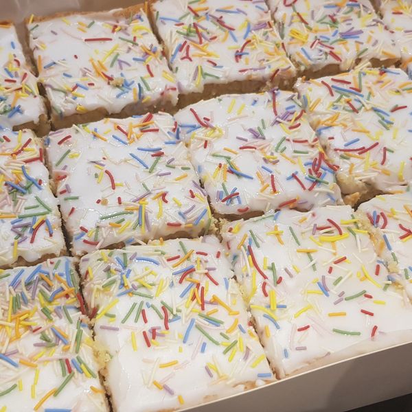 Box of frosted cake squares with colorful sprinkles.