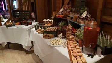 A rustic dessert table with various sweets and a large drink dispenser.