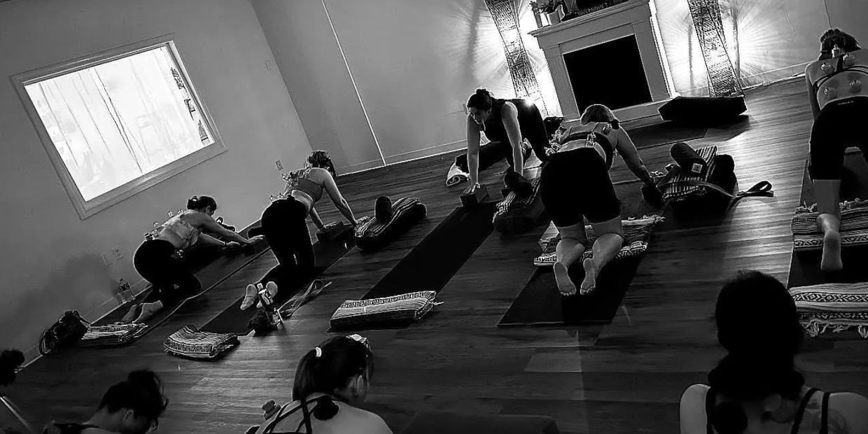 Group yoga session in a calm studio with mats and blocks.