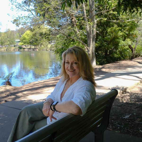 Woman sitting on a bench by a lake smiling.