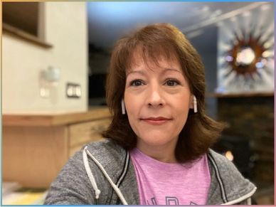 Maria-Lupita Gurule has earbuds on and is smiling while looking forward.