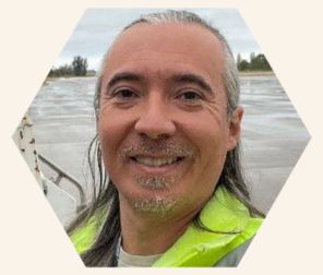 Joseph Banks is smiling while standing on a boat overlooking the waters.