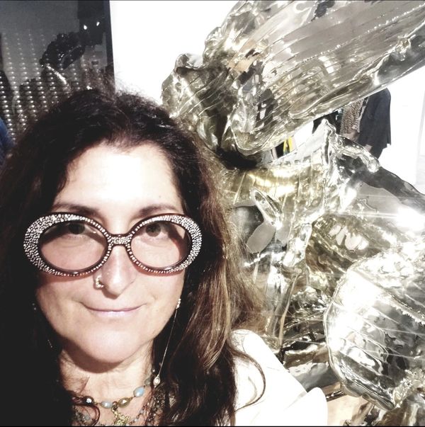 Woman with large rhinestone glasses posing with shiny art.